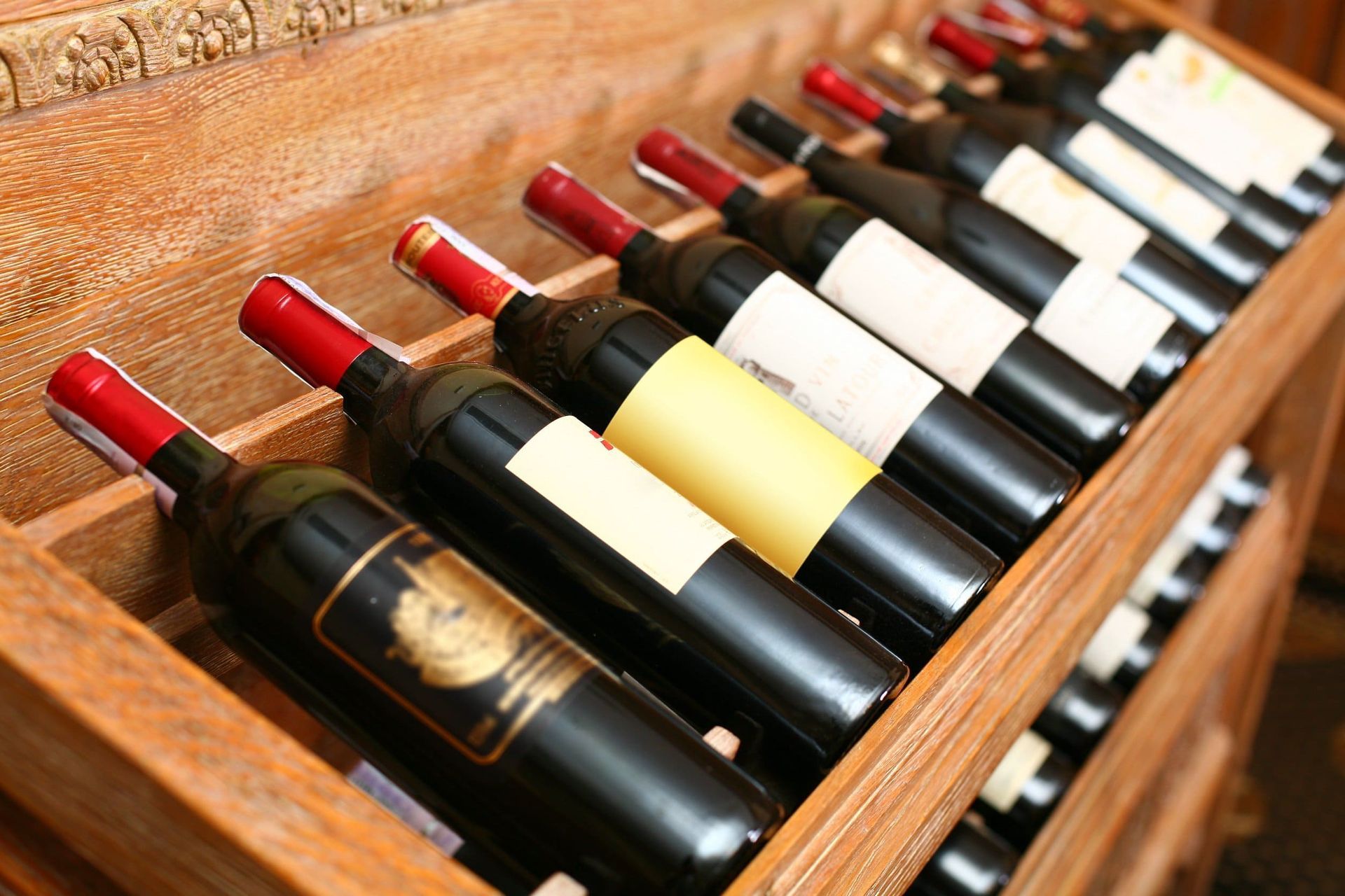 Una fila de botellas de vino están alineadas en un estante de madera.