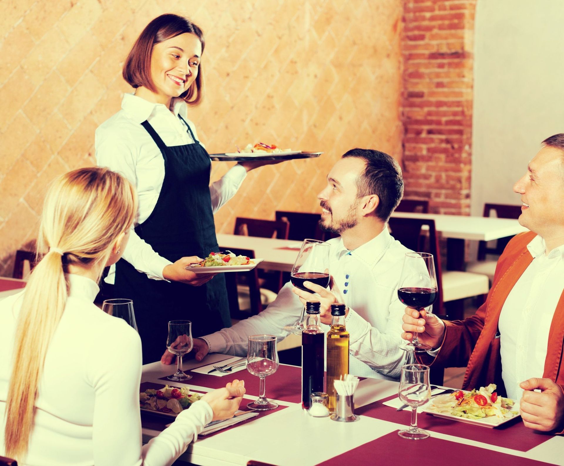 Una camarera está sirviendo comida a un grupo de personas en un restaurante.