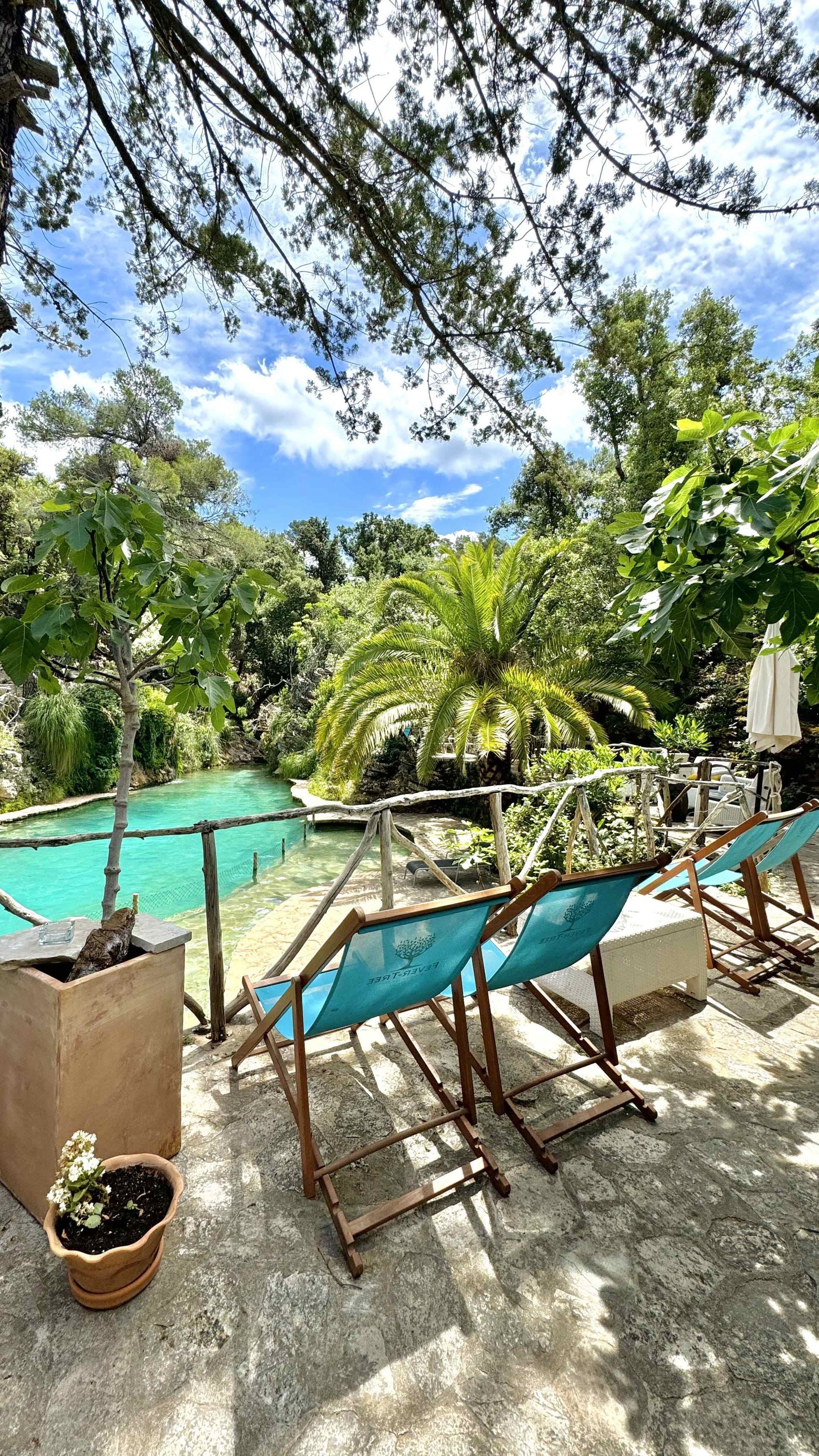 Una fila de sillas de jardín están ubicadas en un patio al lado de una piscina.