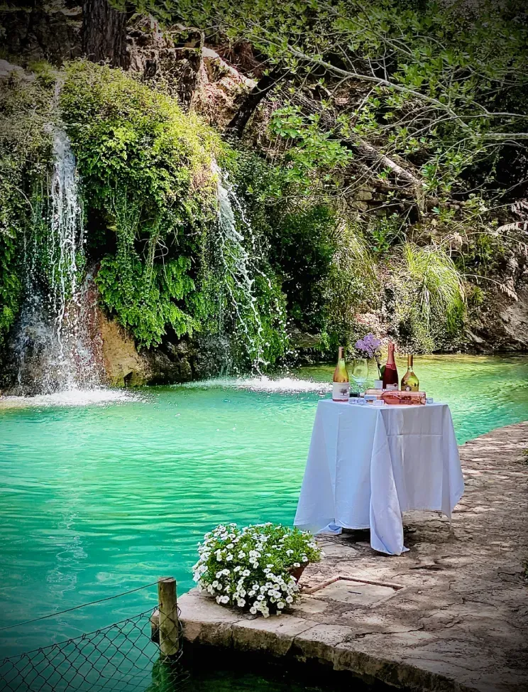 Una mesa con un mantel blanco está sentada al lado de una cascada.