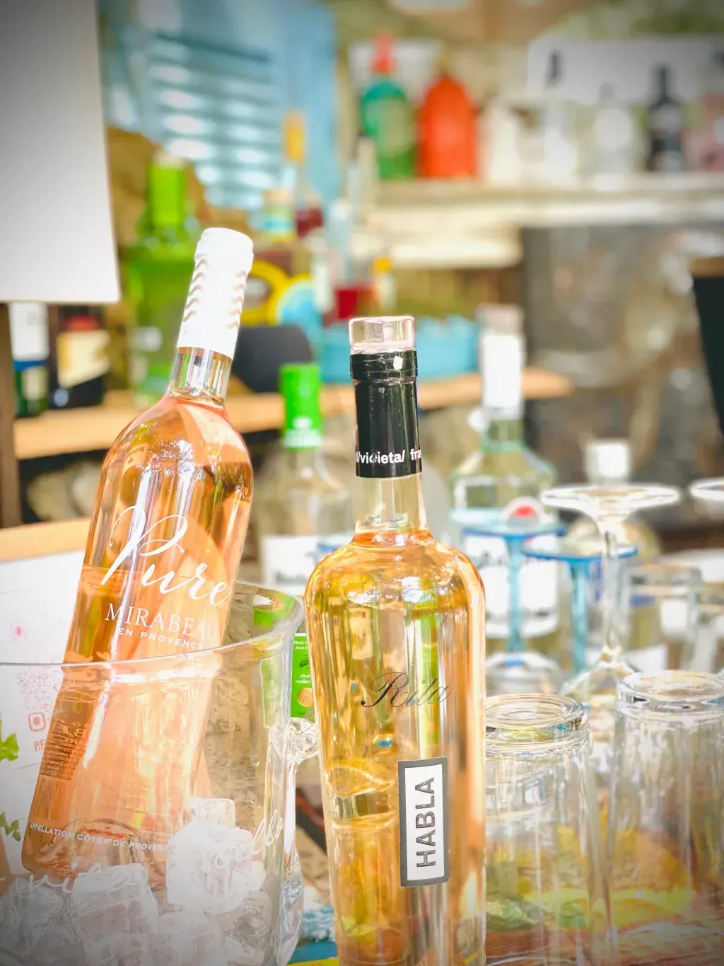 Una botella de vino está en un cubo de hielo al lado de un vaso.