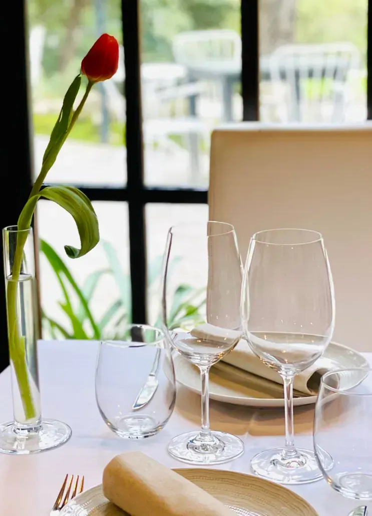 Una mesa puesta con platos, vasos y un jarrón de flores.
