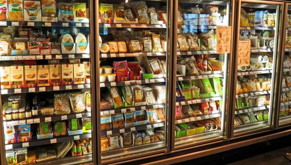 Vitrina refrigerada de alimentos en una tienda, llena de diversos alimentos envasados.