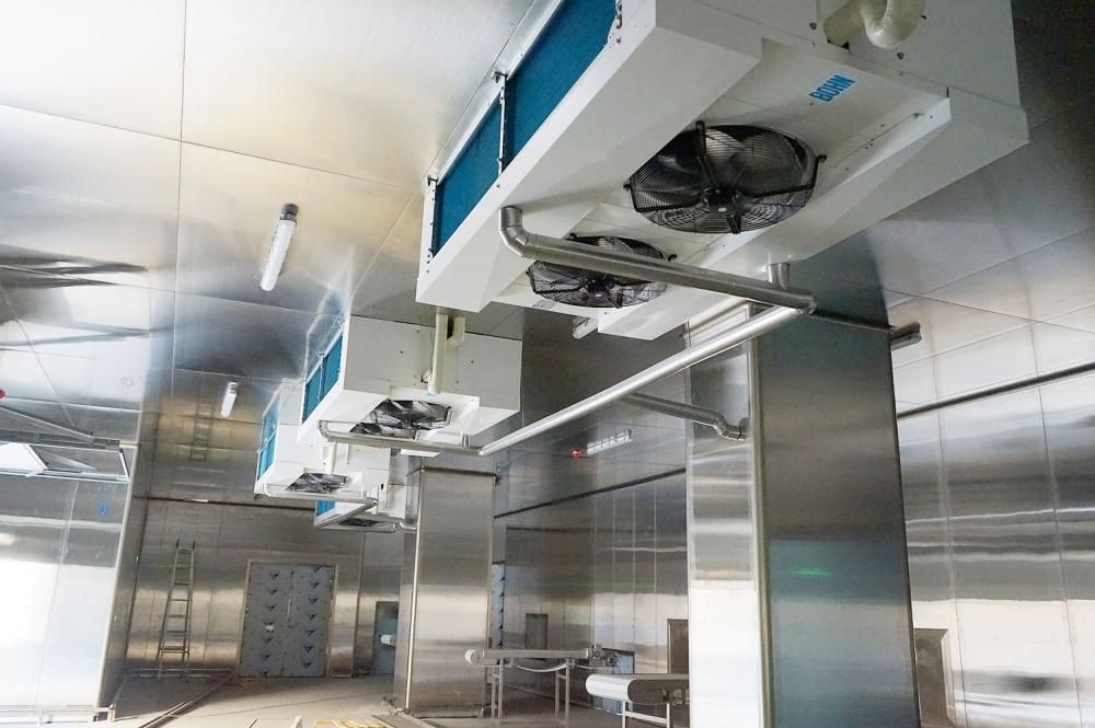 Interior de cafetería con bebidas en vitrina refrigerada, vino y una pequeña mesa con una silla.