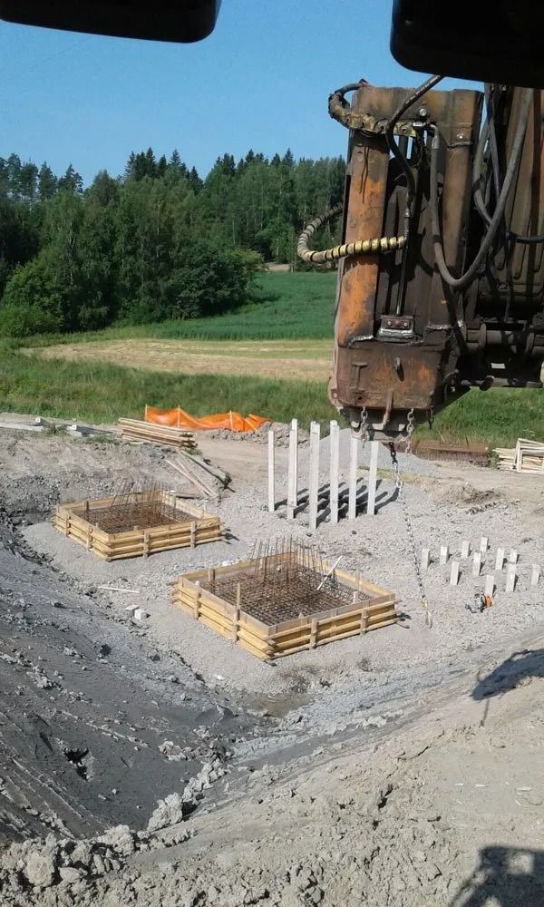 Rakennustyömaa porauslautan, raudoitustankojen ja puisten muottien kanssa soralla metsäalueen lähellä