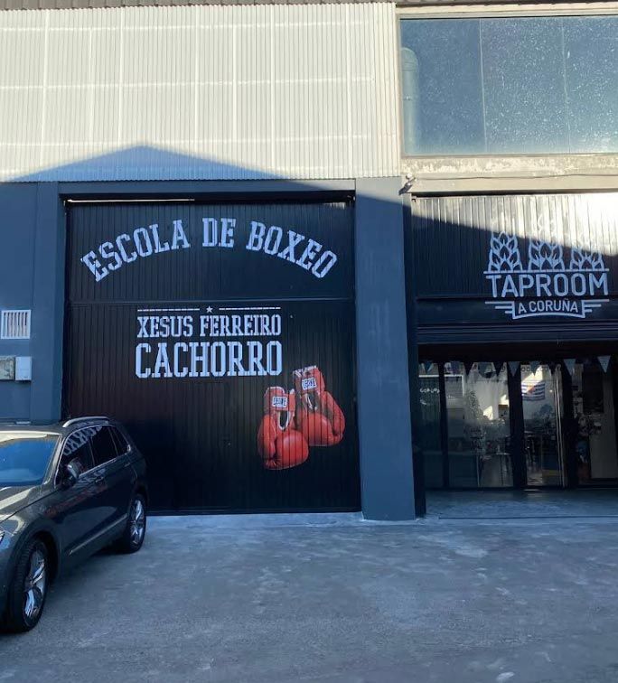 Un coche negro está aparcado delante de un edificio que dice escuela de boxeo