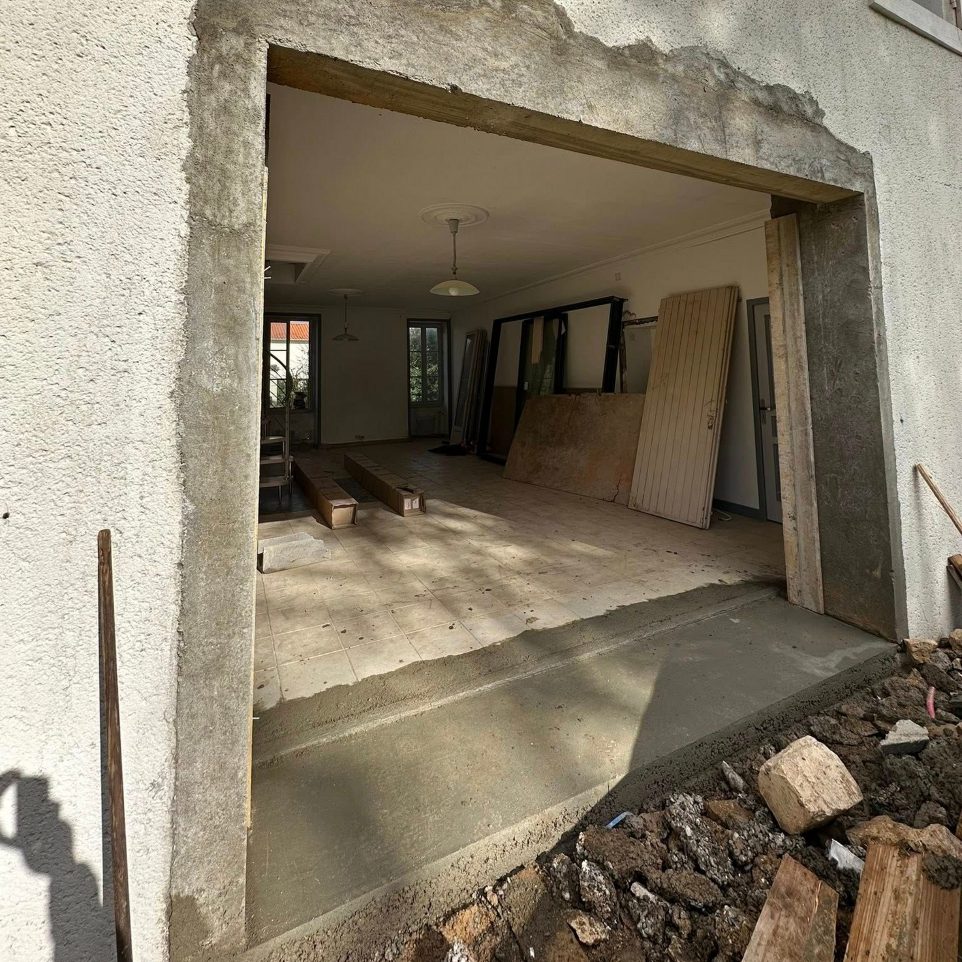 Porte extérieure en construction, montrant un sol en béton et une structure avec vue intérieure d'une pièce.