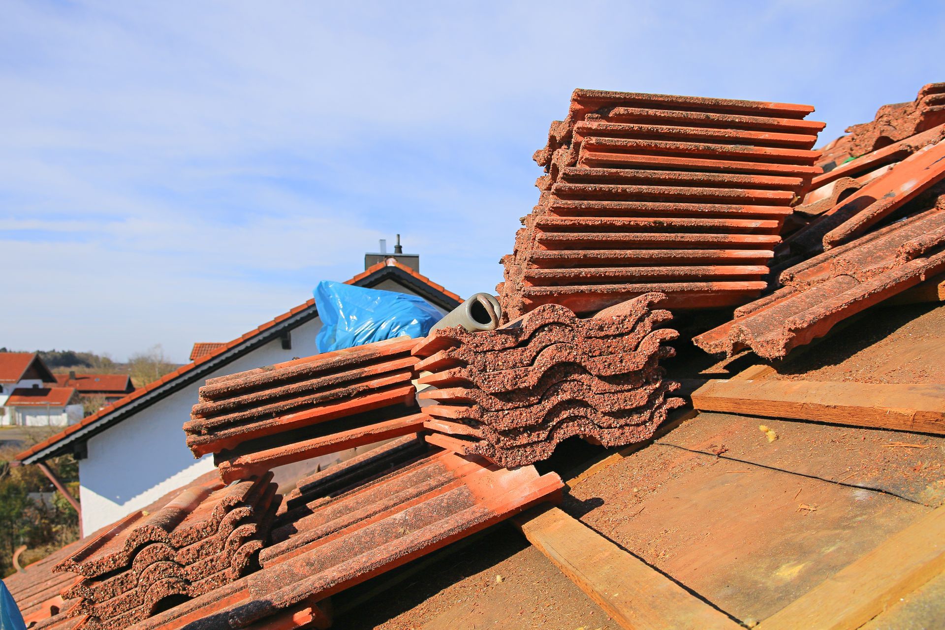 Des piles de tuiles rouges sur le toit d'une maison lors de travaux de réparation par une journée ensoleillée.