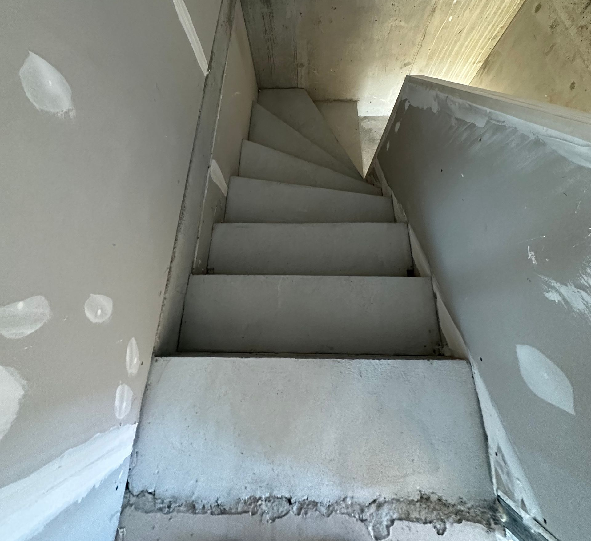 Chantier : escalier en béton inachevé, poutres de soutien en bois et bétonnière.