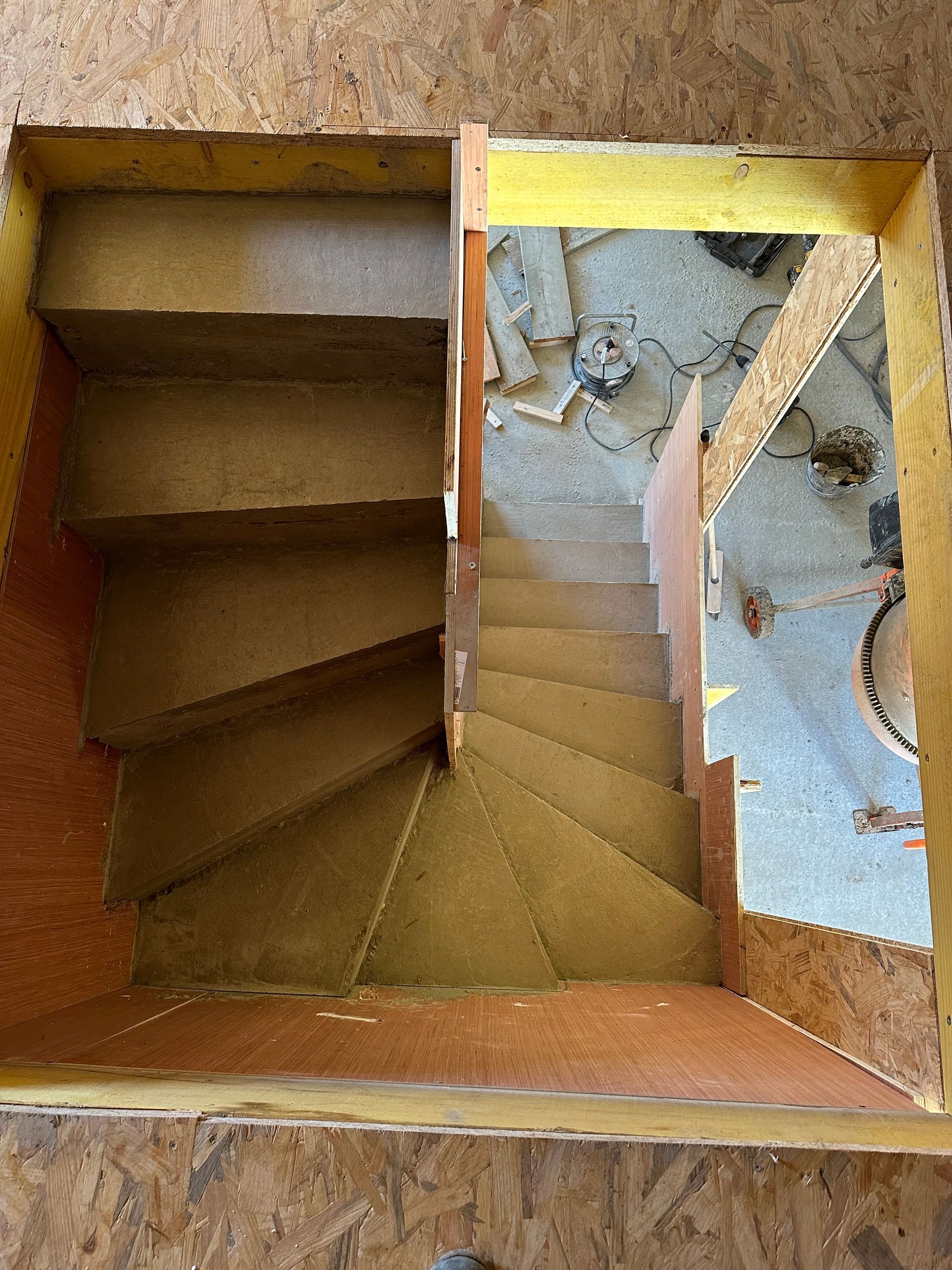 Construction d'un escalier à ossature bois avec cadre jaune. Vue de dessus révélant les marches et la structure environnante.
