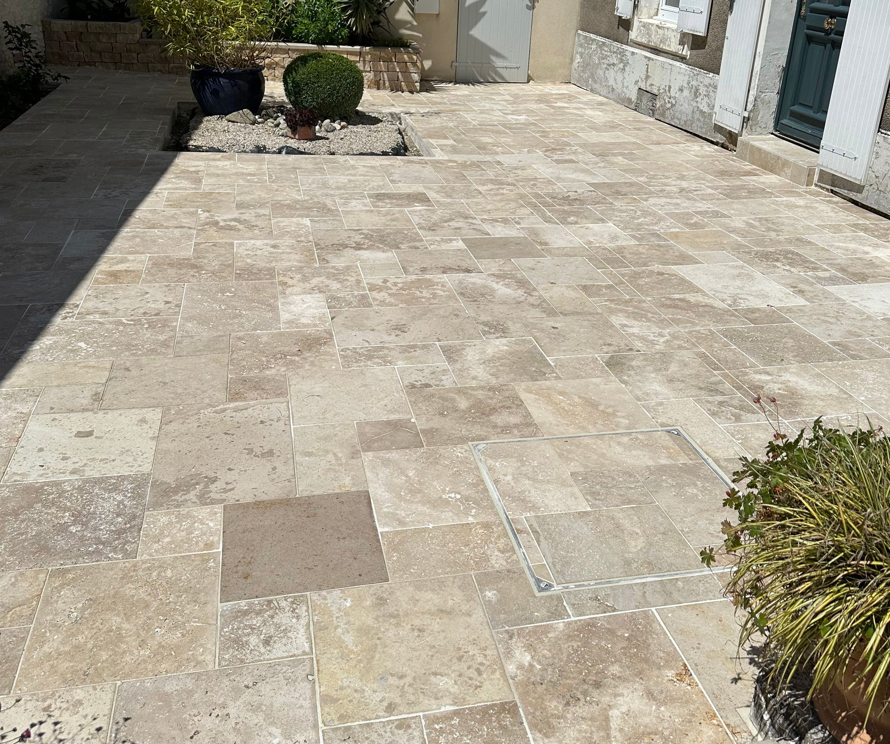 Vue aérienne de la piscine à l'eau bleu foncé, de la terrasse claire et de deux chaises longues noires.