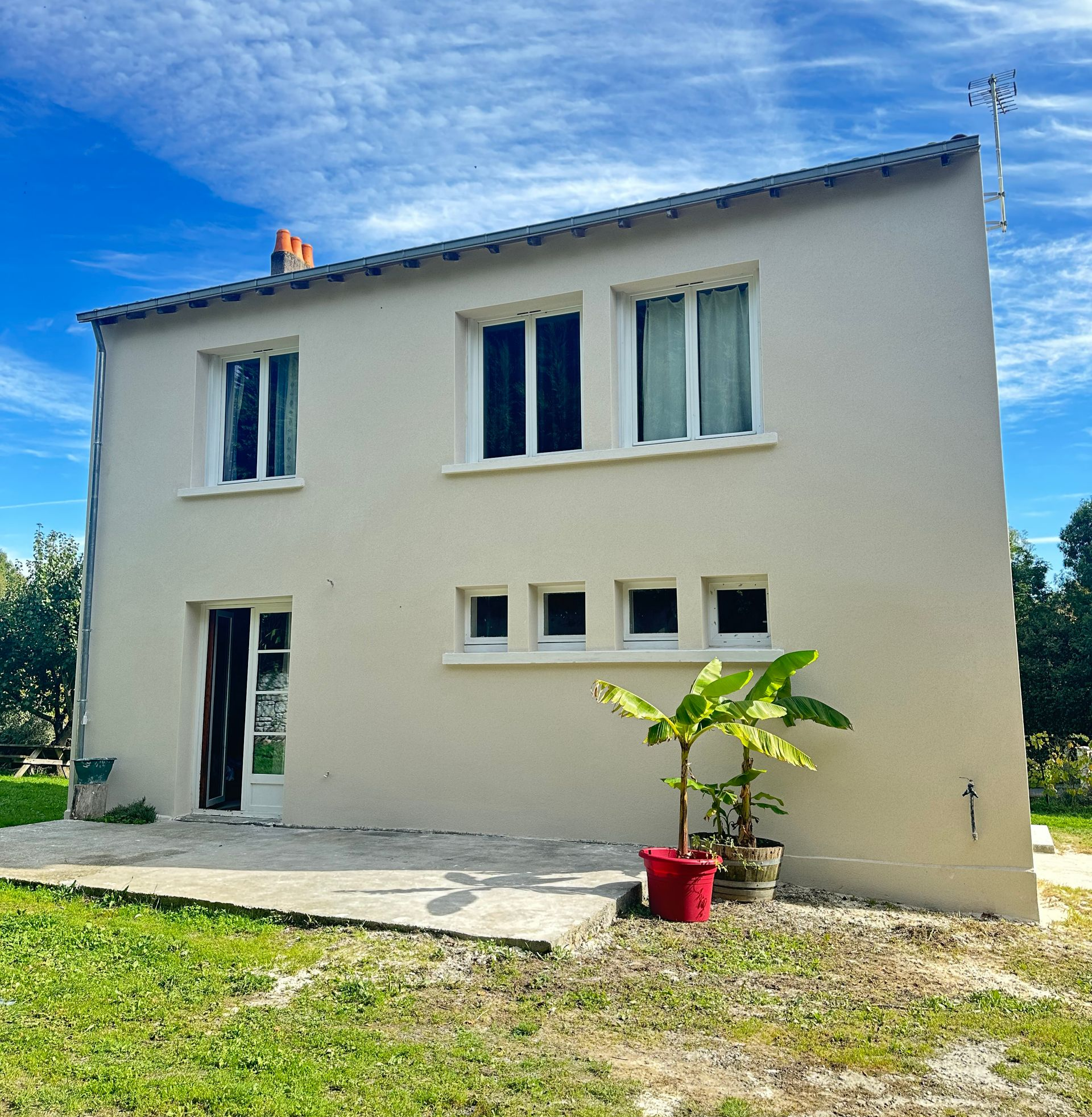 Porte d'entrée noire avec fenêtre cintrée et imposte latérale, encastrée dans une façade en pierre.
