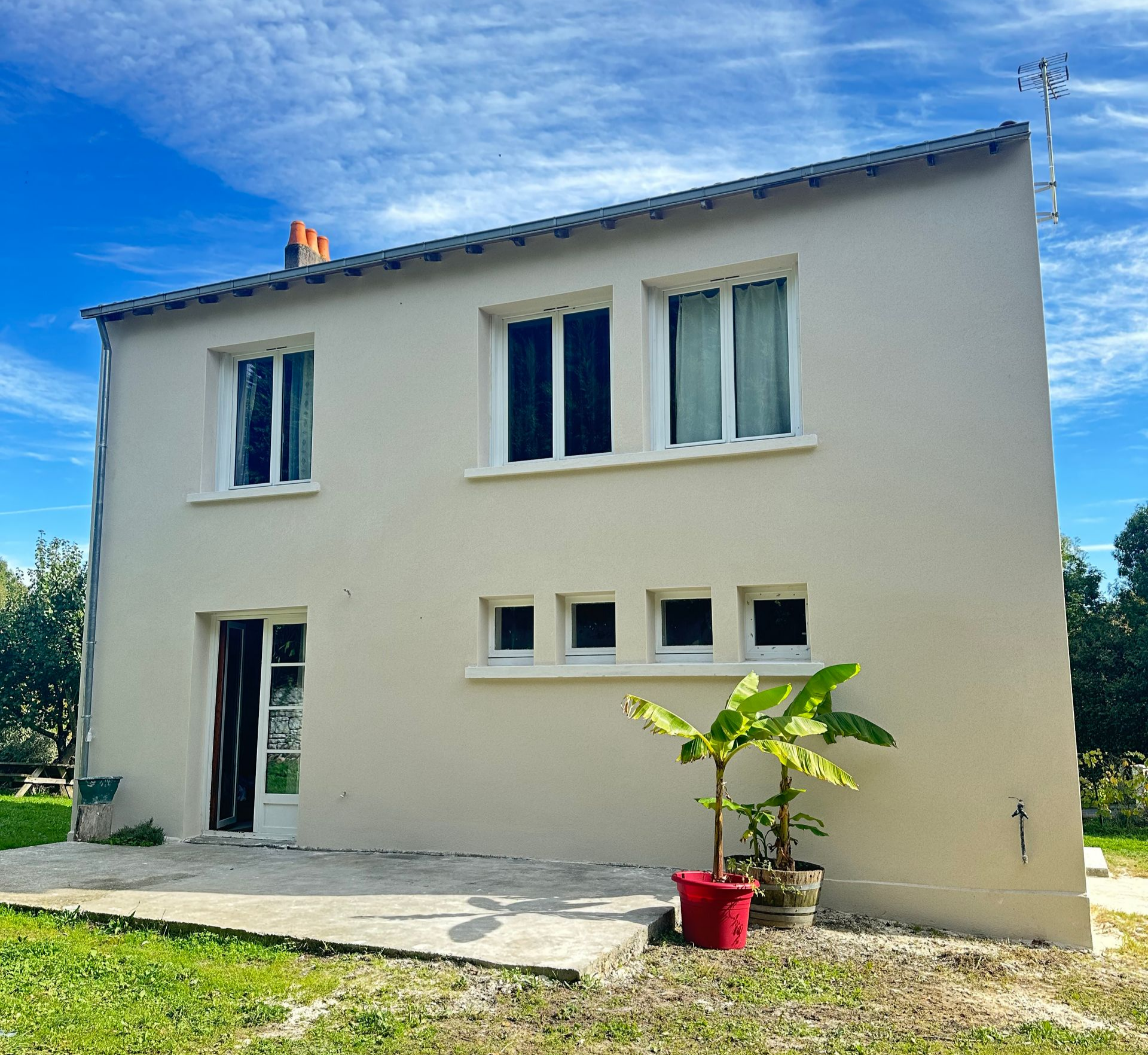 Bâtiment en pierre avec une fenêtre à volets blancs en partie supérieure et une fenêtre à volets jaunes en partie inférieure.