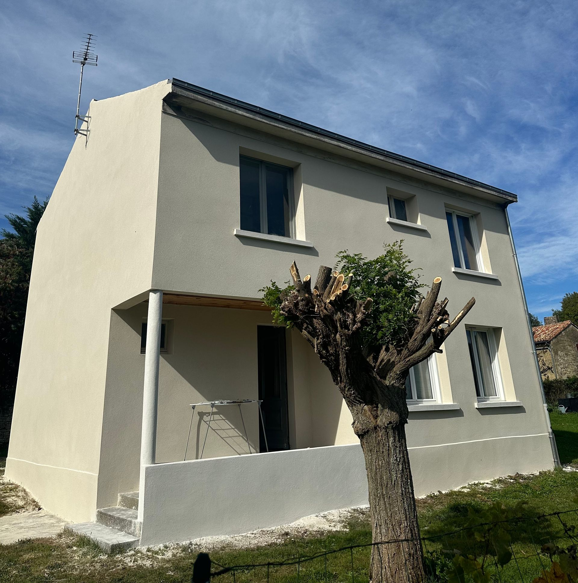 Bâtiment en pierre avec volets jaunes et blancs. Fenêtre à l'étage, deux fenêtres au rez-de-chaussée.