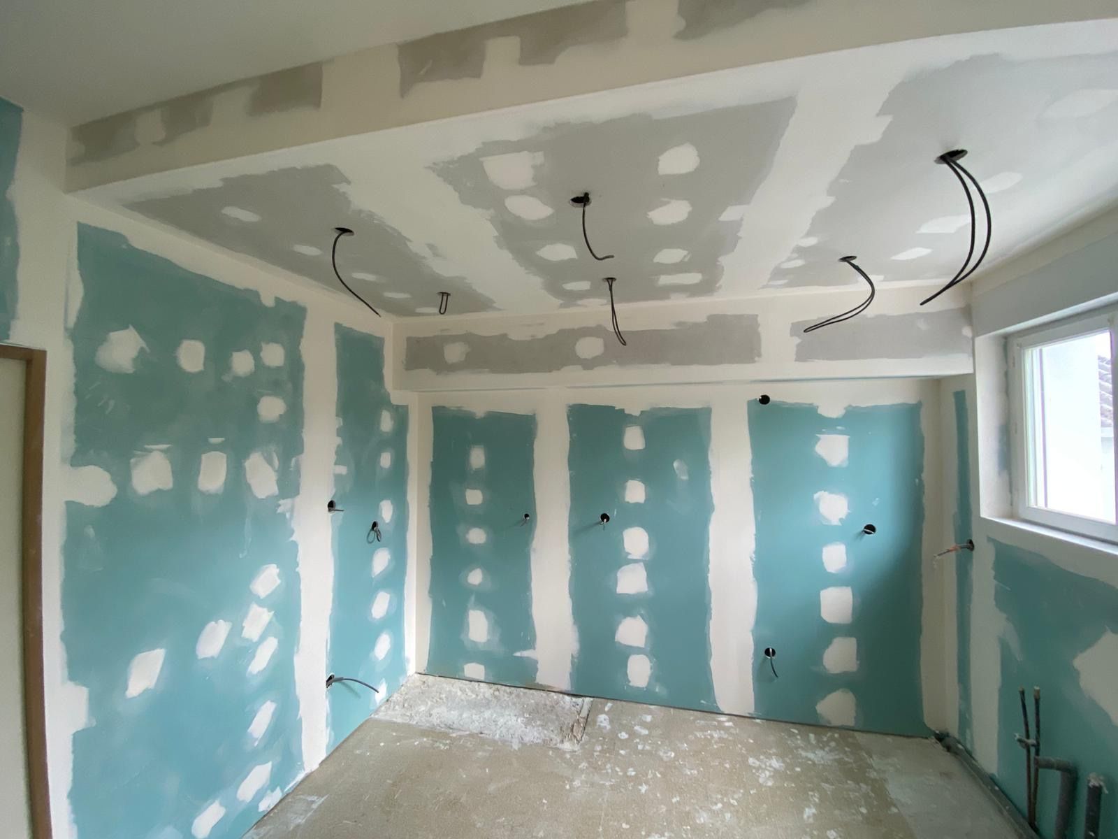 Pièce intérieure avec murs et plafond en plaques de plâtre non finies, câblage électrique apparent.