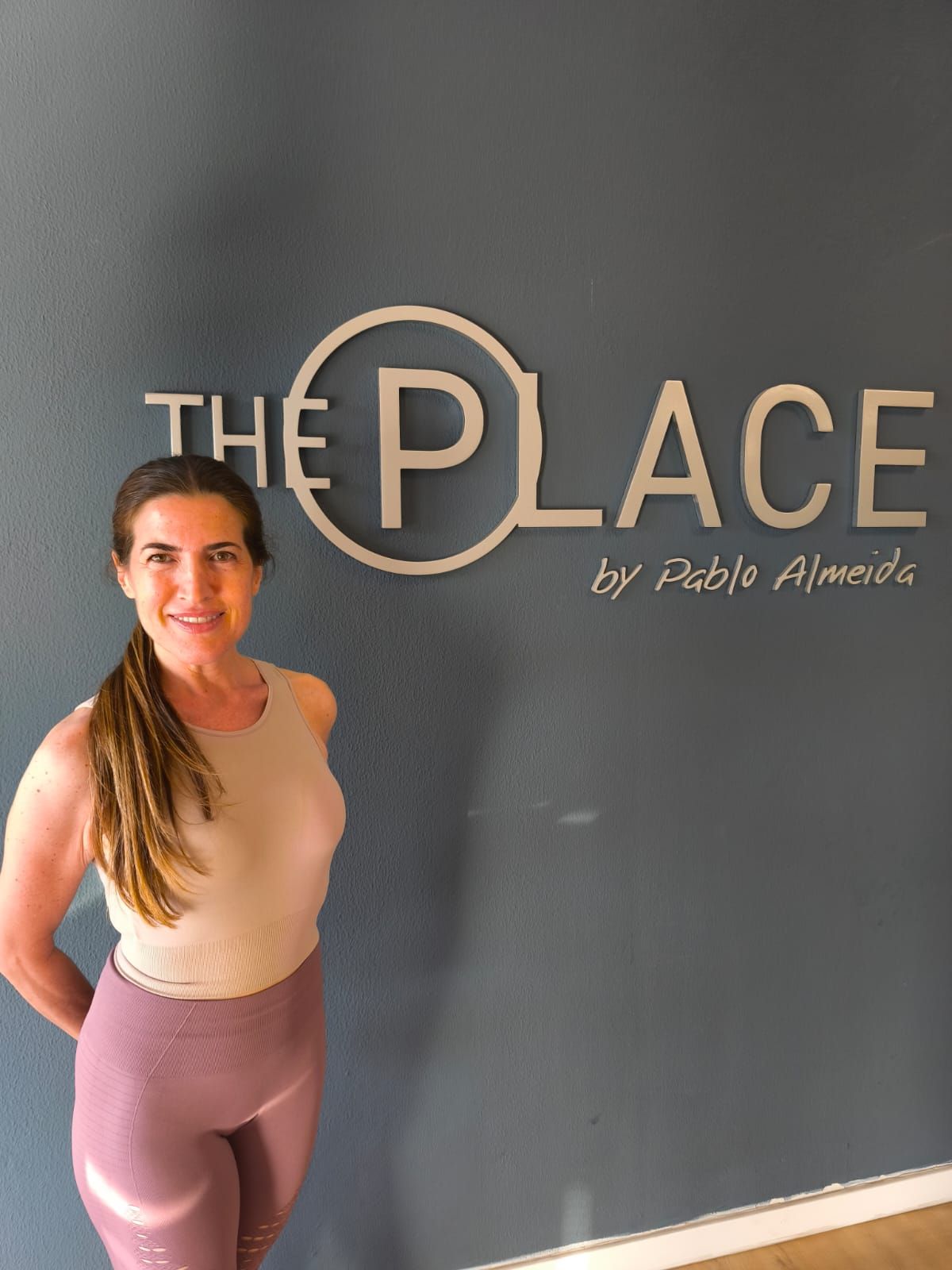 Una mujer sonríe frente a un cartel de 