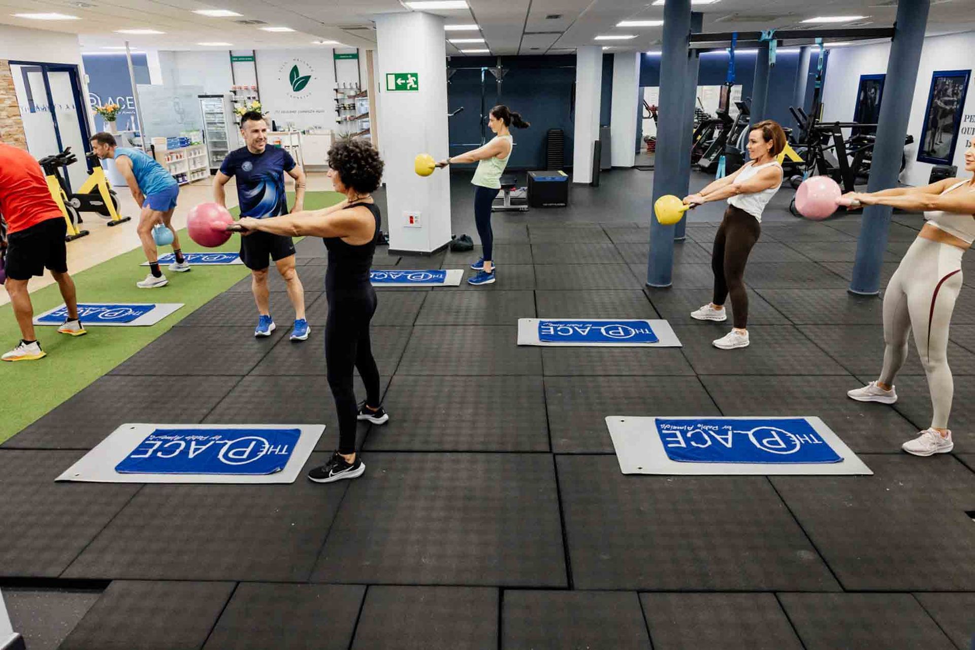Personas en un gimnasio haciendo ejercicios con pesas rusas.