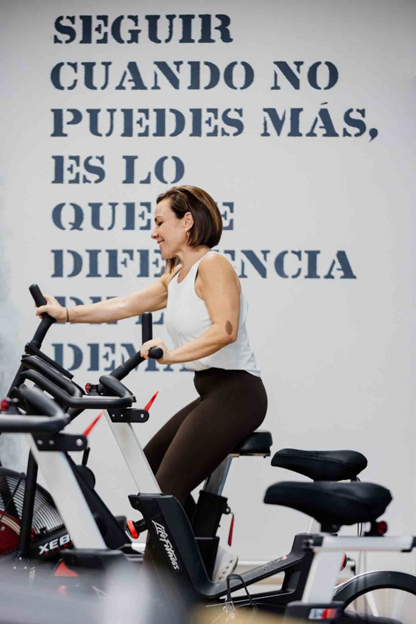 Una mujer hace ejercicio en una bicicleta estática en un gimnasio. 