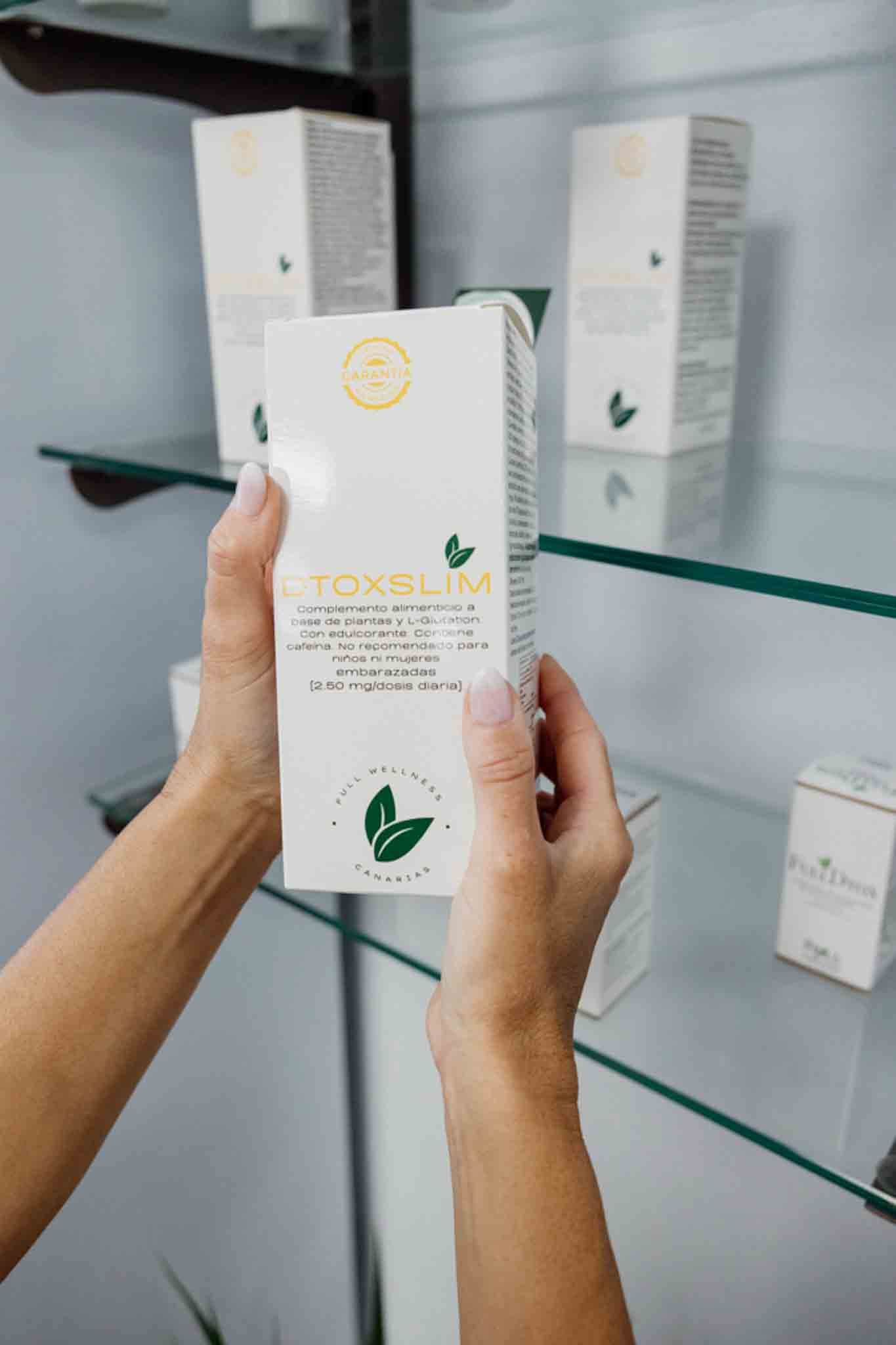 Mujer sosteniendo una caja de producto para el cuidado de la piel de color blanco con un logotipo de hoja verde.