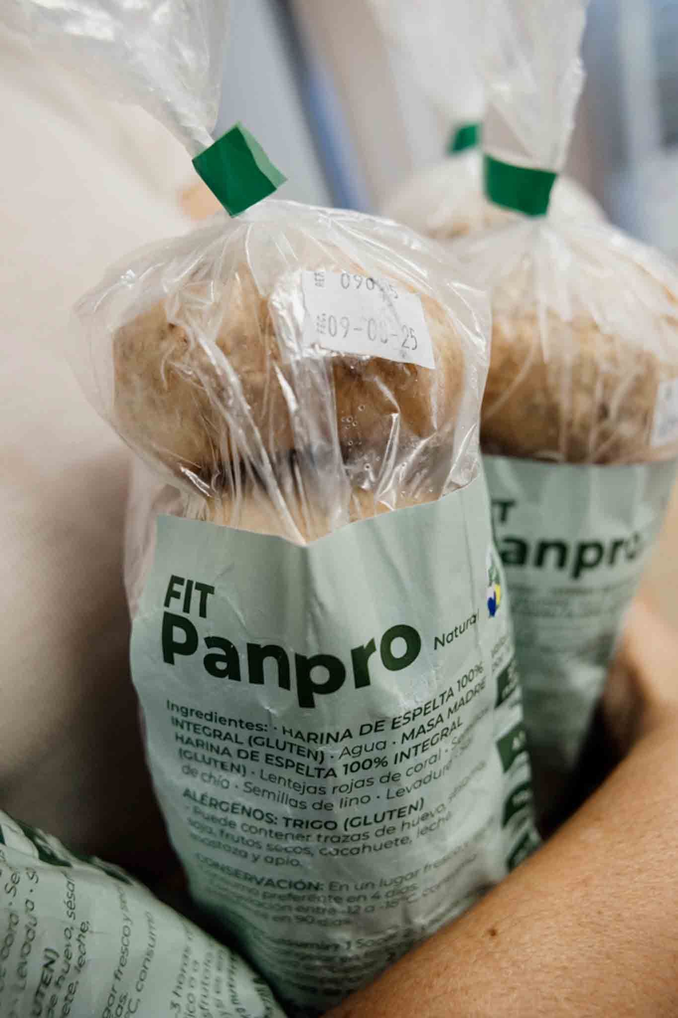 Alguien sostiene en brazos bolsas de pan selladas con cierres verdes. Las bolsas llevan la etiqueta 