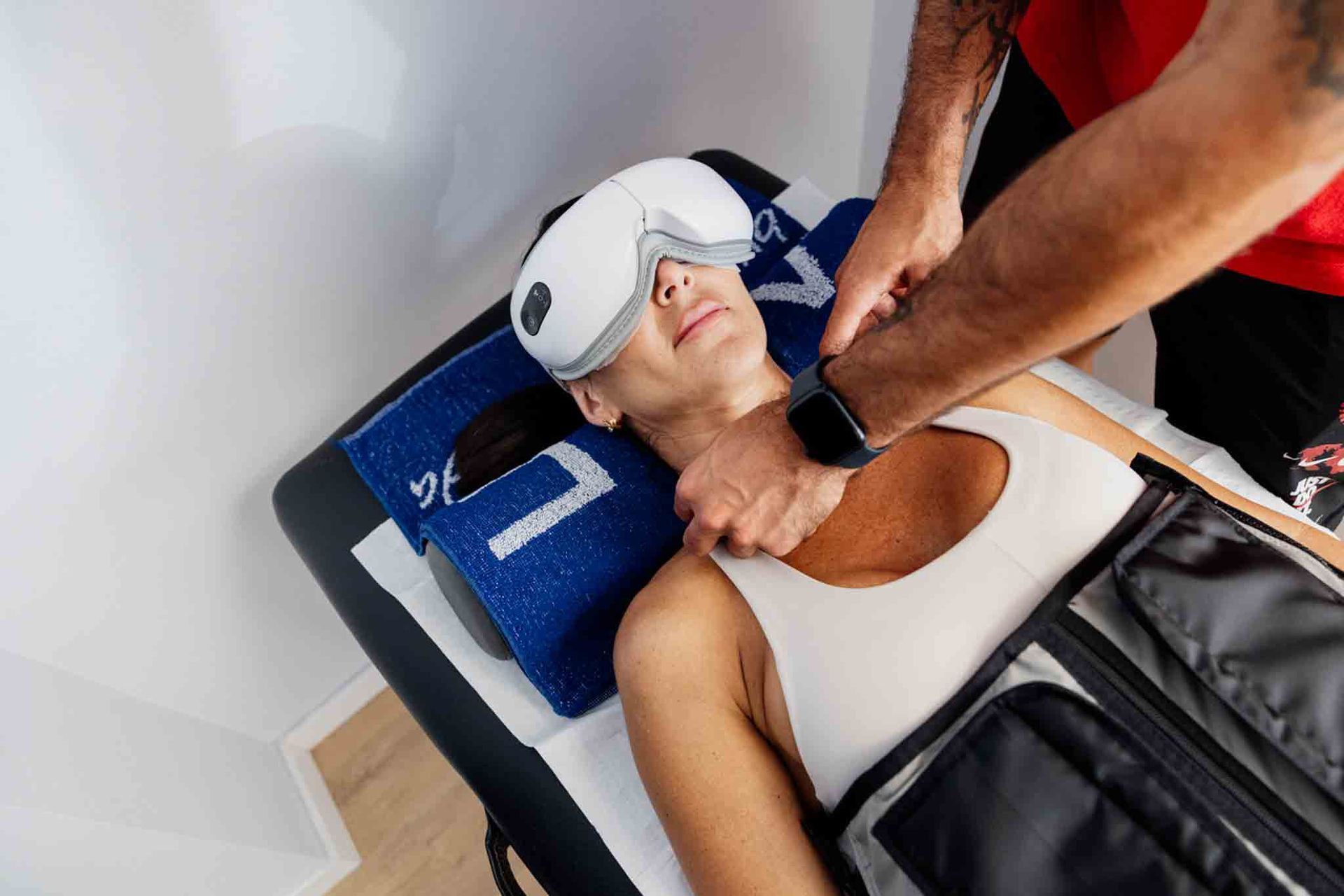 Una persona con antifaz recibe un masaje cervical. Está tumbada en una camilla de masaje.