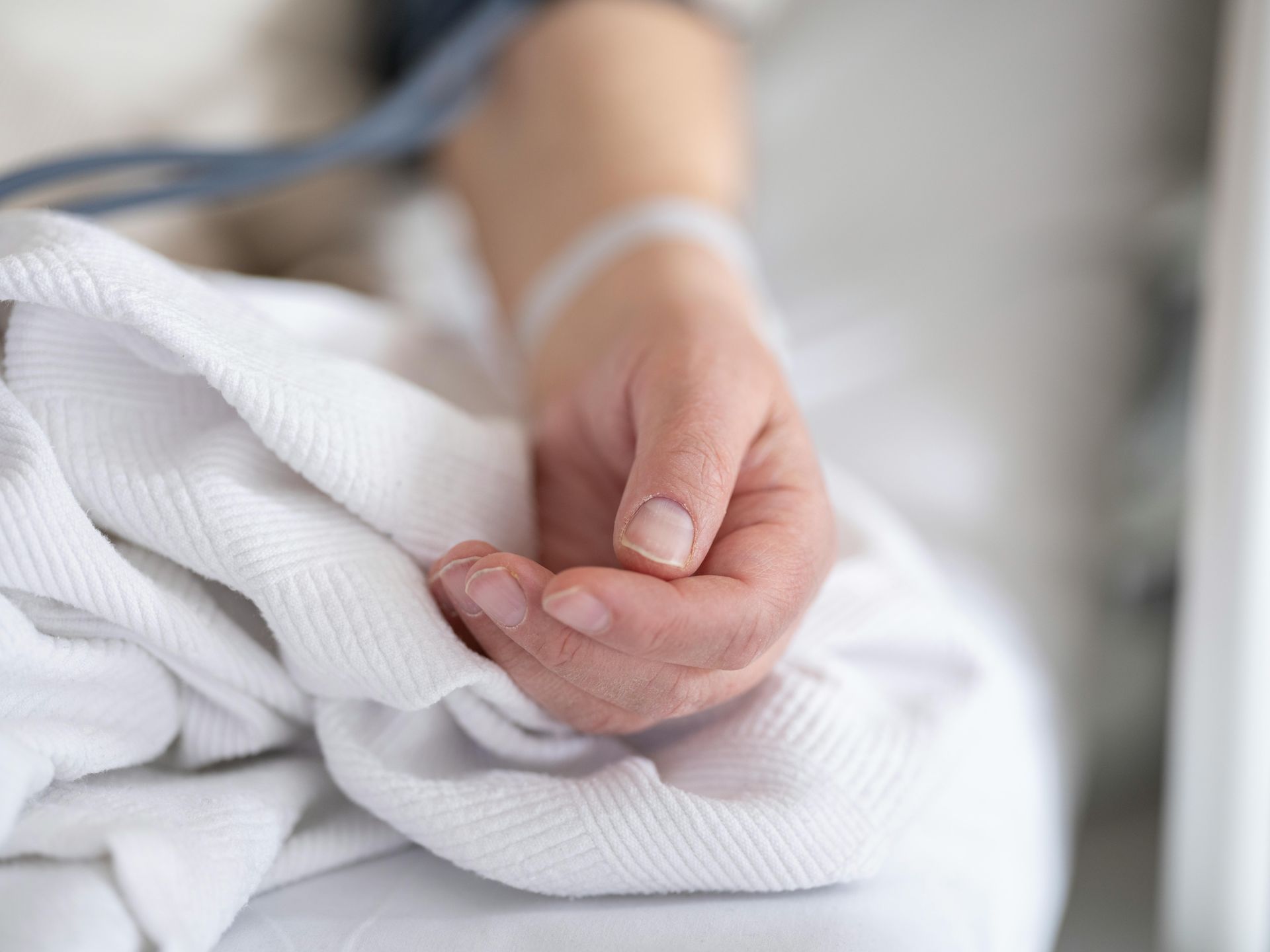 Main d'une personne repose sur un drap blanc