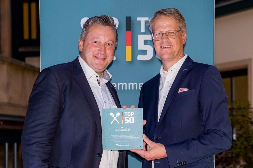 Zwei Männer in Anzügen halten ein Schild mit der Aufschrift x150
