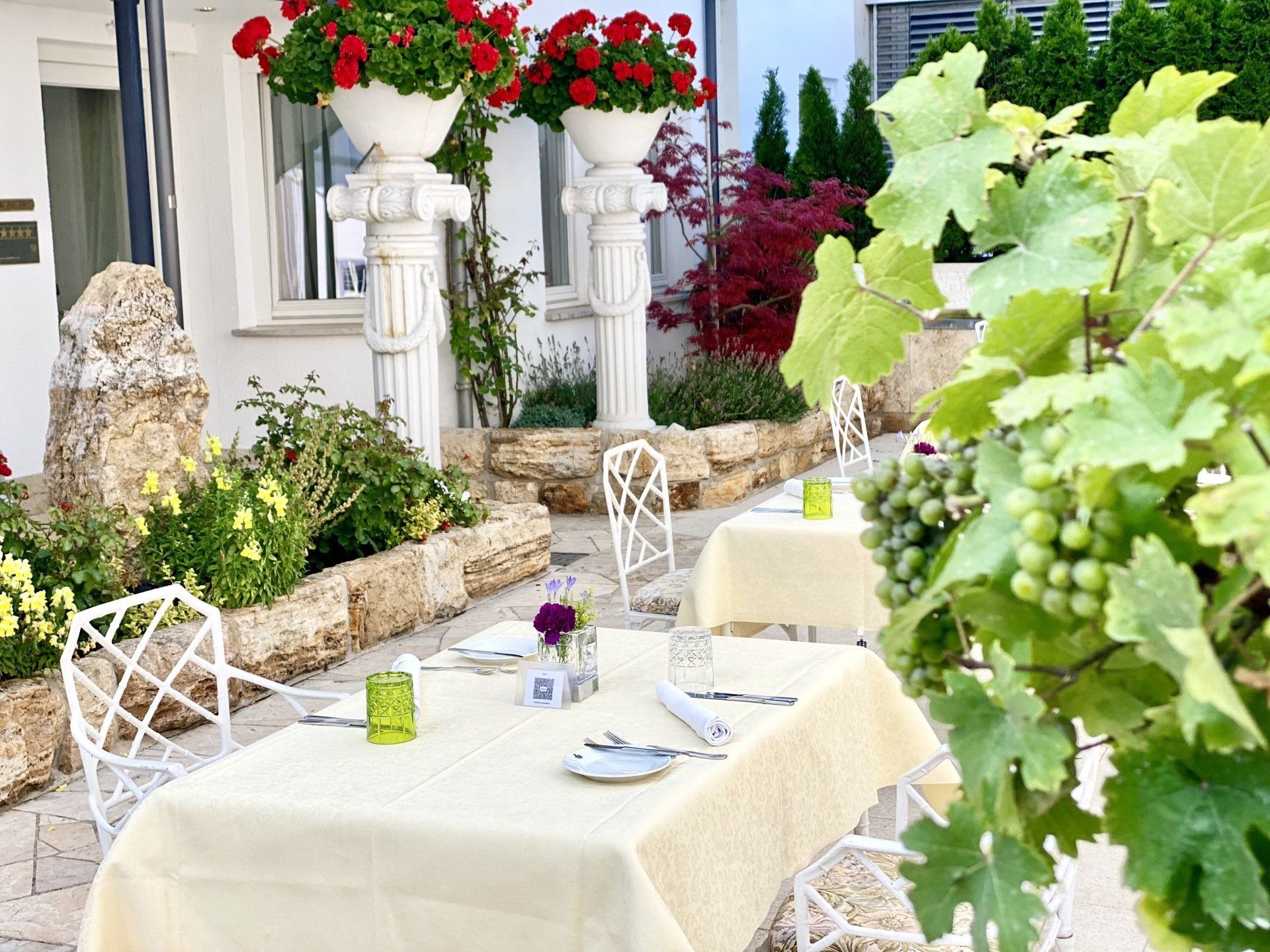 Eine Terrasse mit Tischen und Stühlen und Blumen im Hintergrund