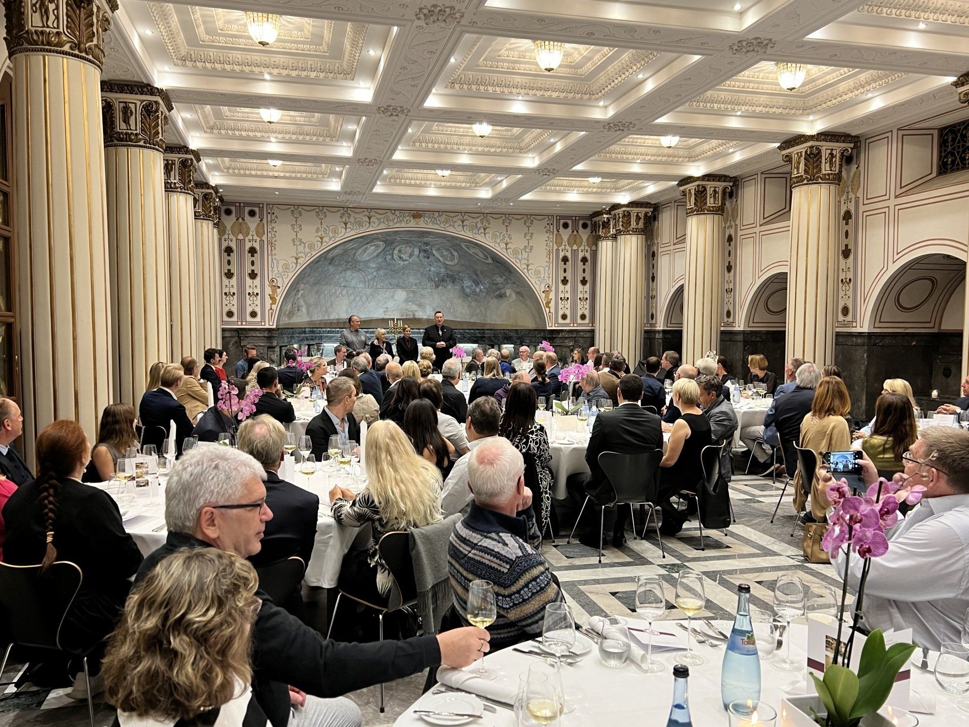 Eine große Gruppe von Menschen sitzt an Tischen in einem großen Raum