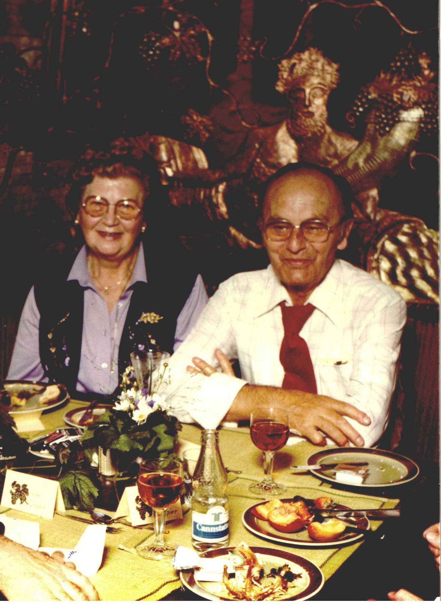 Ein Mann und eine Frau sitzen an einem Tisch mit Tellern voller Essen und einer Flasche Wasser