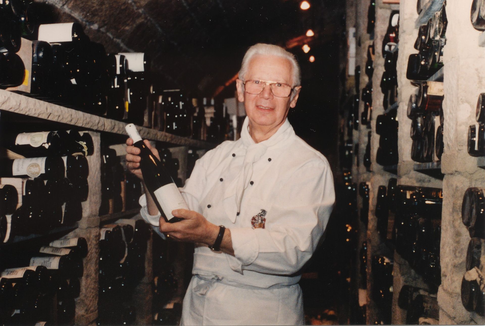 Ein Mann hält eine Flasche Wein in einem Weinkeller