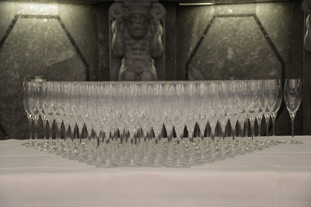 Eine Reihe von Weingläsern auf einem Tisch mit einer Statue im Hintergrund