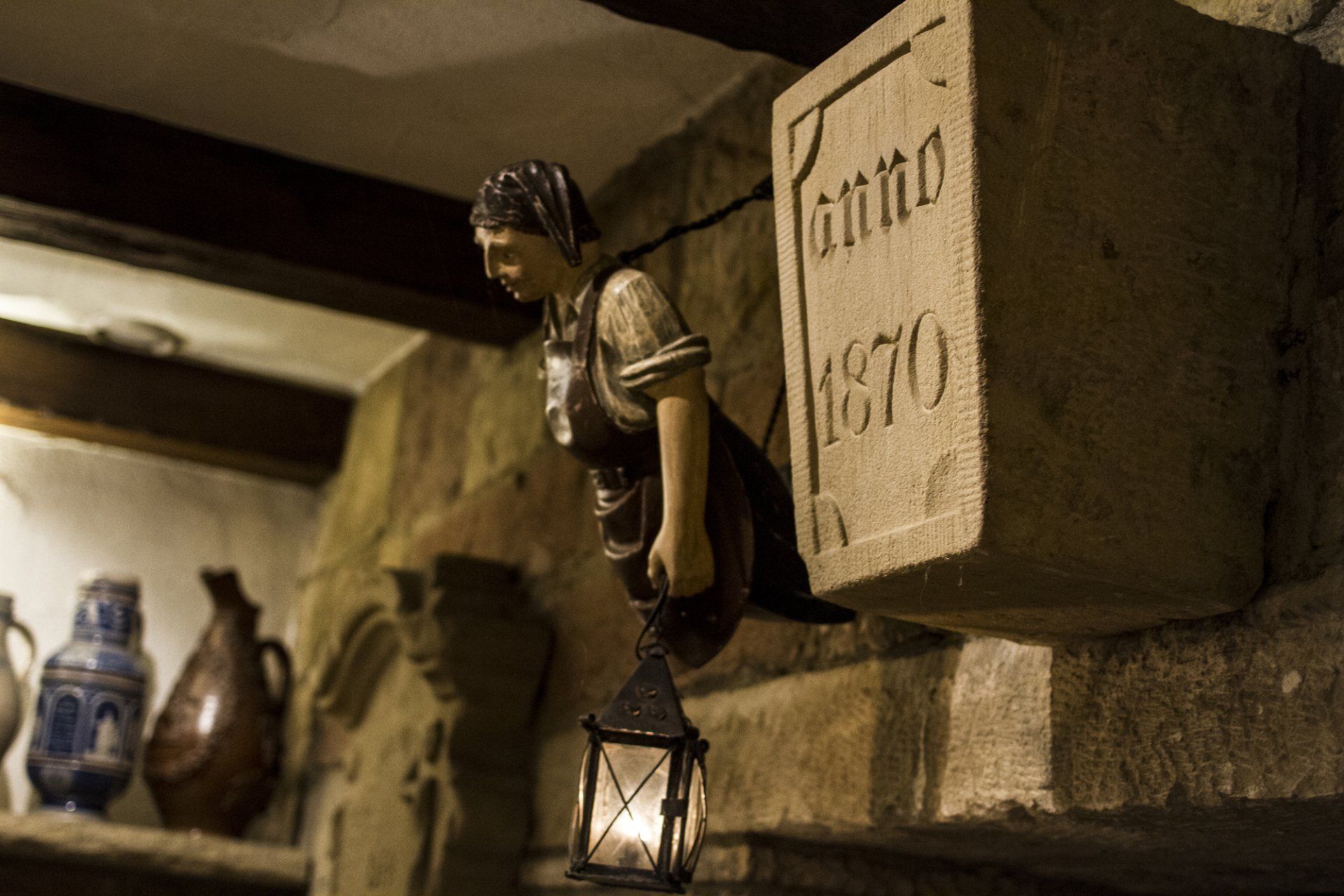 Eine Statue eines Mannes mit einer Laterne hängt an einer Steinmauer, auf der steht „Anno 1670“