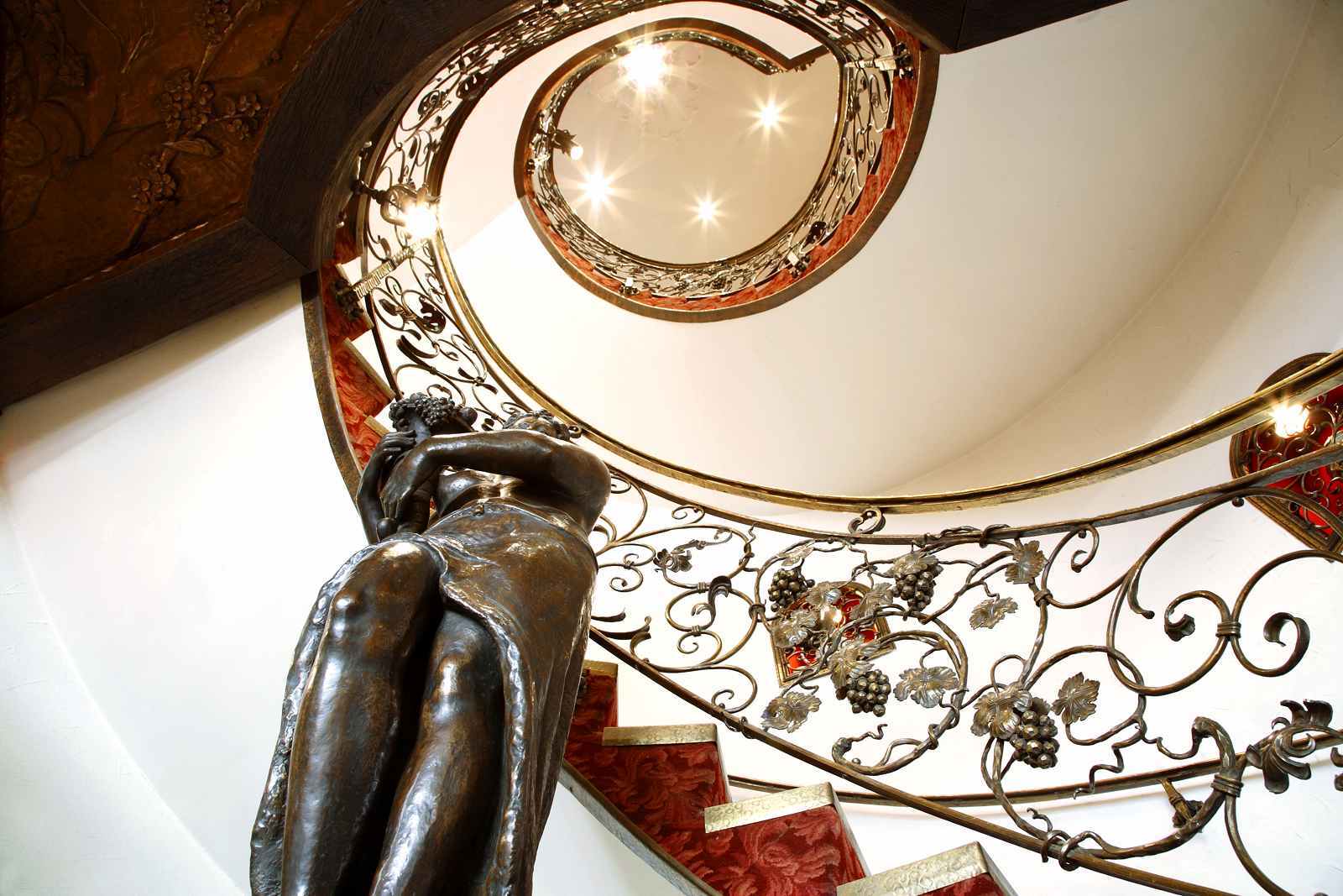 Eine Wendeltreppe mit einem schmiedeeisernen Geländer und einer Statue