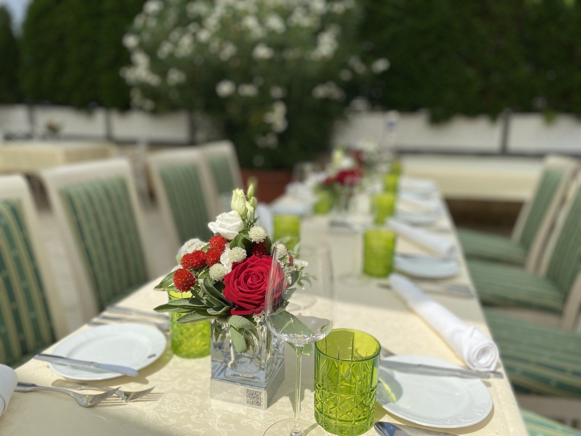Ein langer Tisch mit Tellern, Gläsern und Blumen darauf