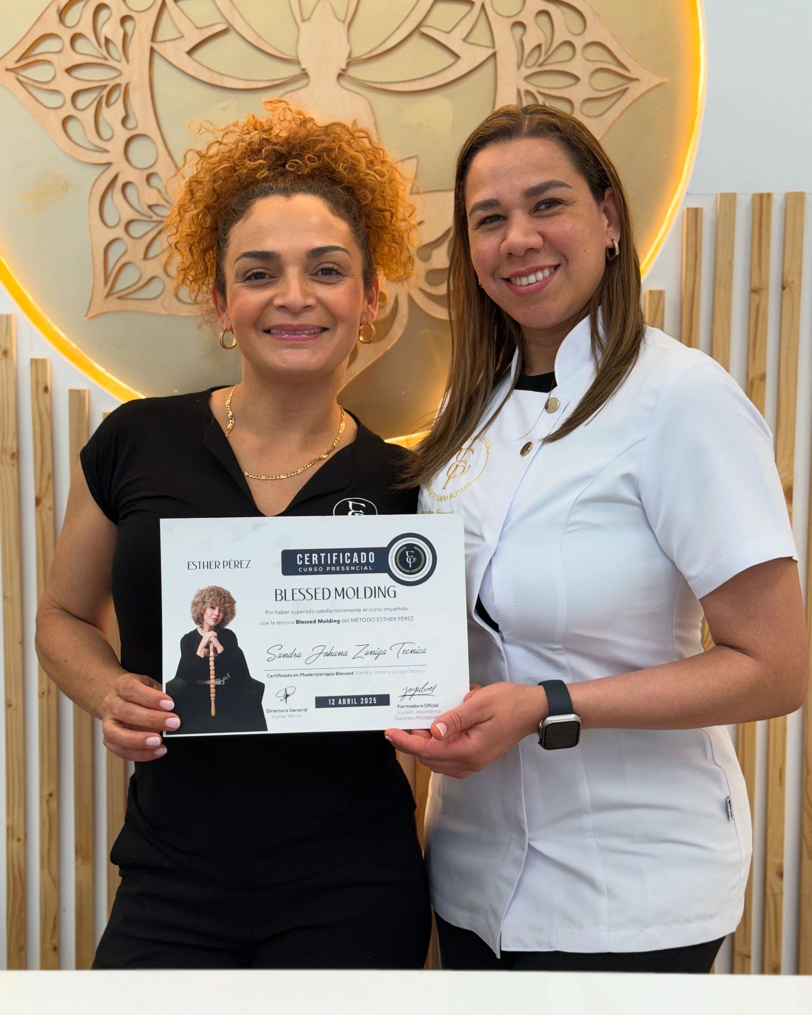 Dos mujeres sonriendo, sosteniendo un certificado.