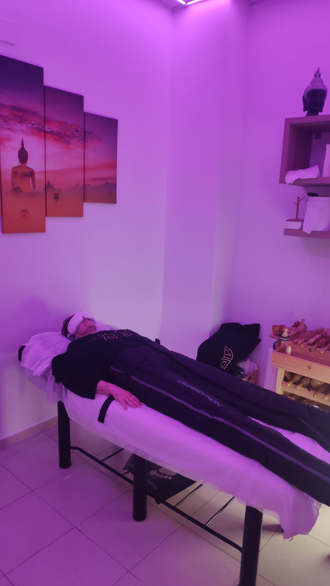 Persona relajándose en una camilla de masaje en una habitación con luz violeta.