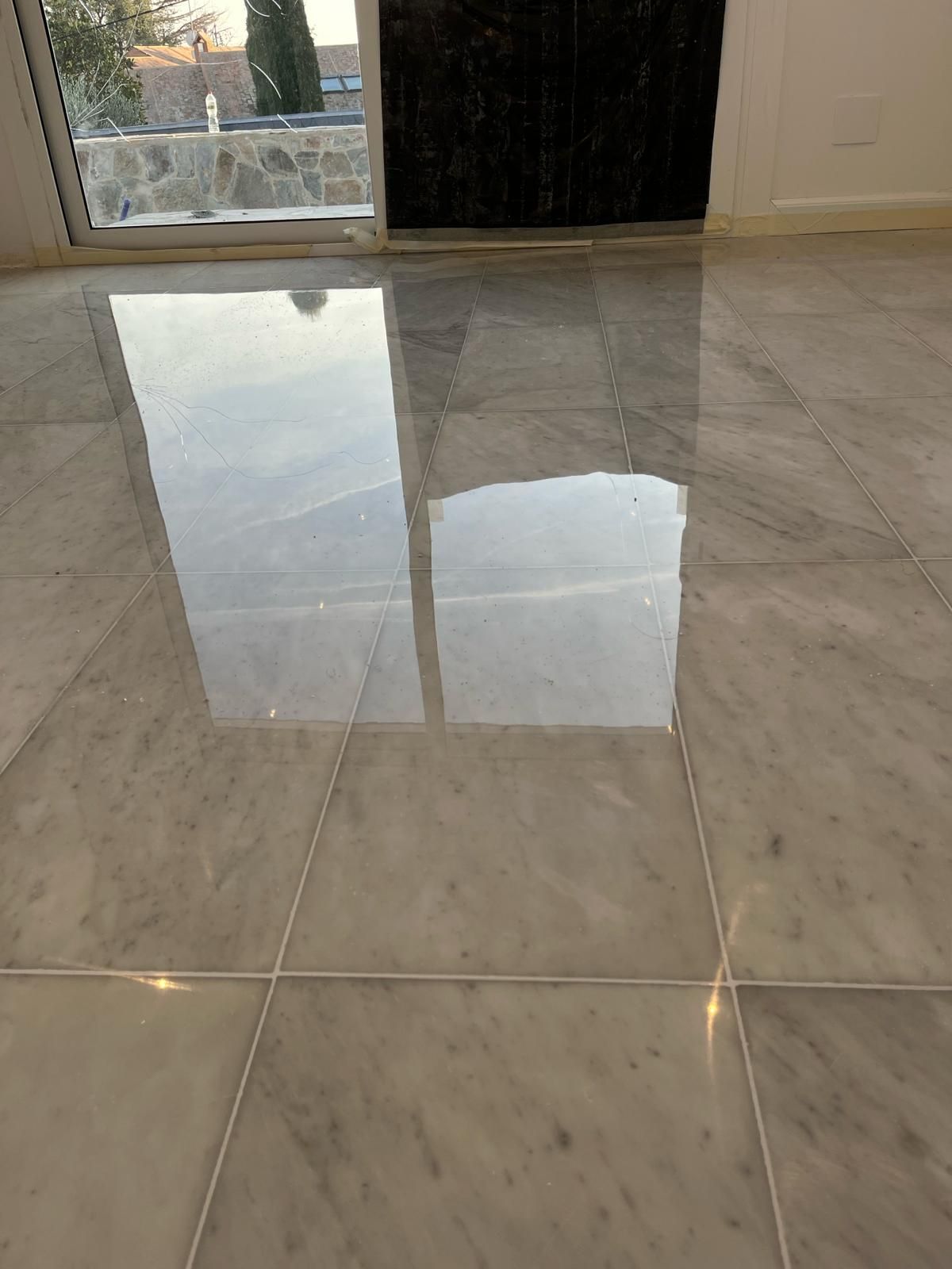 Un suelo de mármol con el reflejo de una ventana.