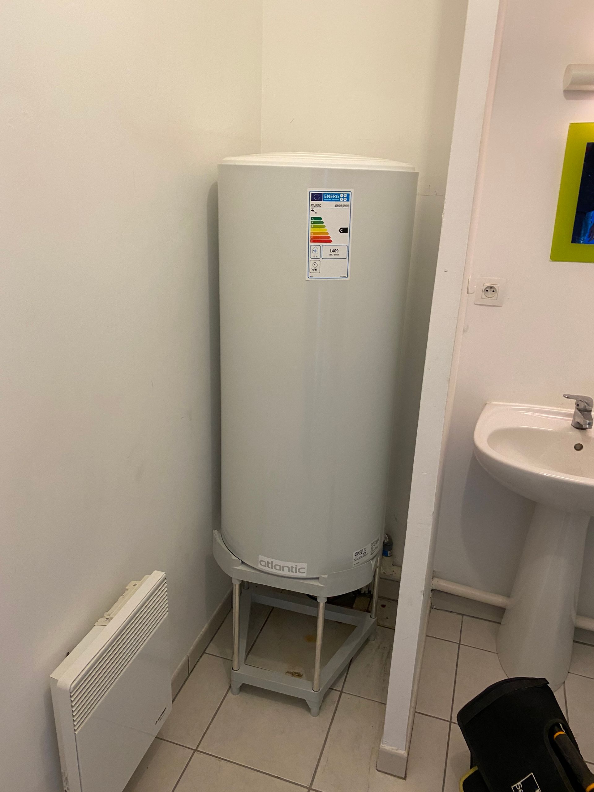 Un grand chauffe-eau est installé dans un coin, à côté d'un petit évier blanc.