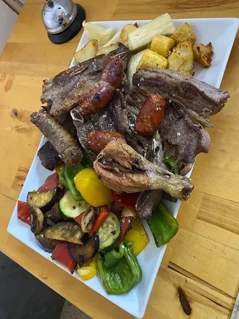 Un plato de carne y verduras en una mesa de madera.