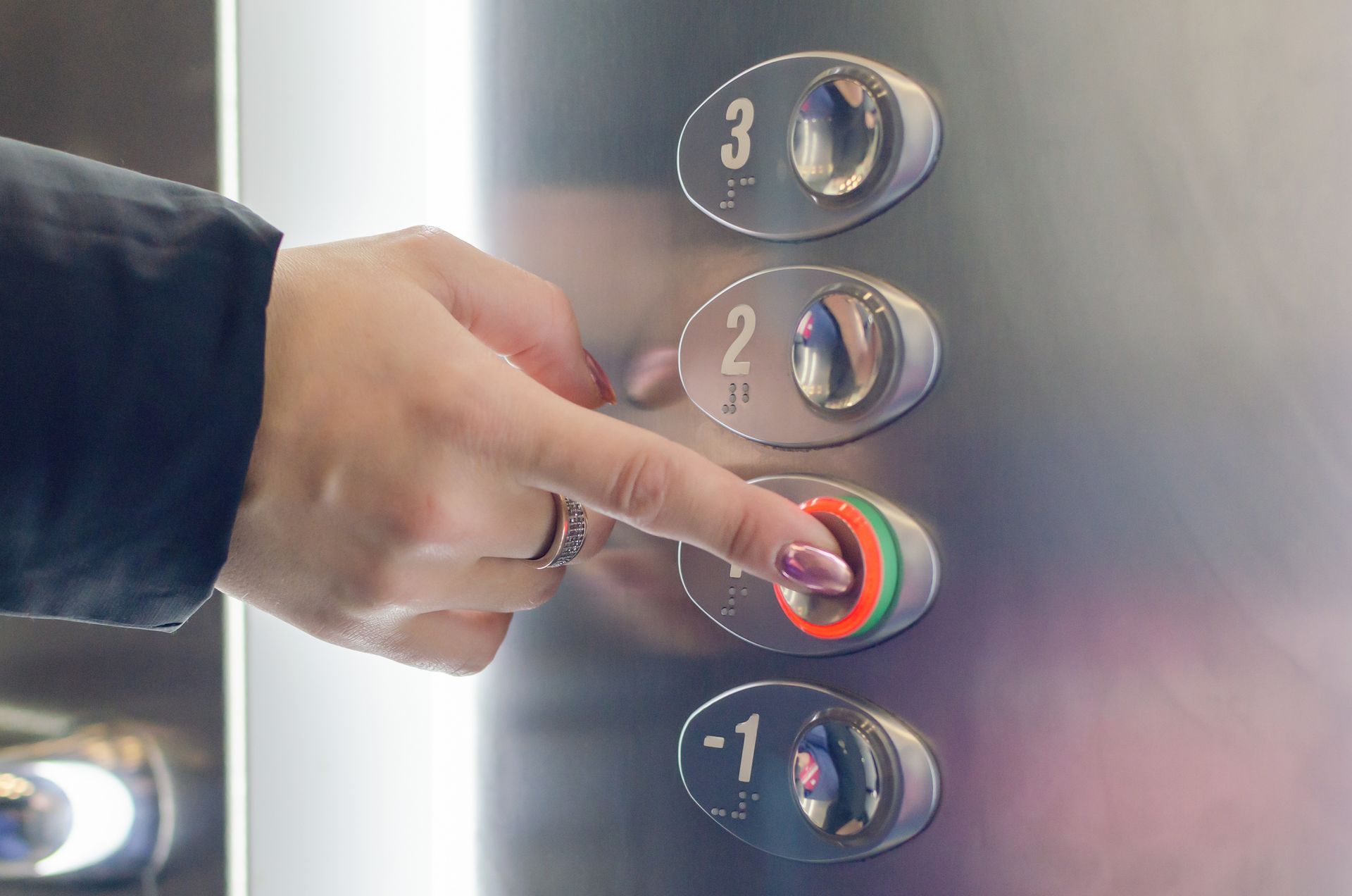 Main de femme  sur le boutons 0 d'un ascenseur