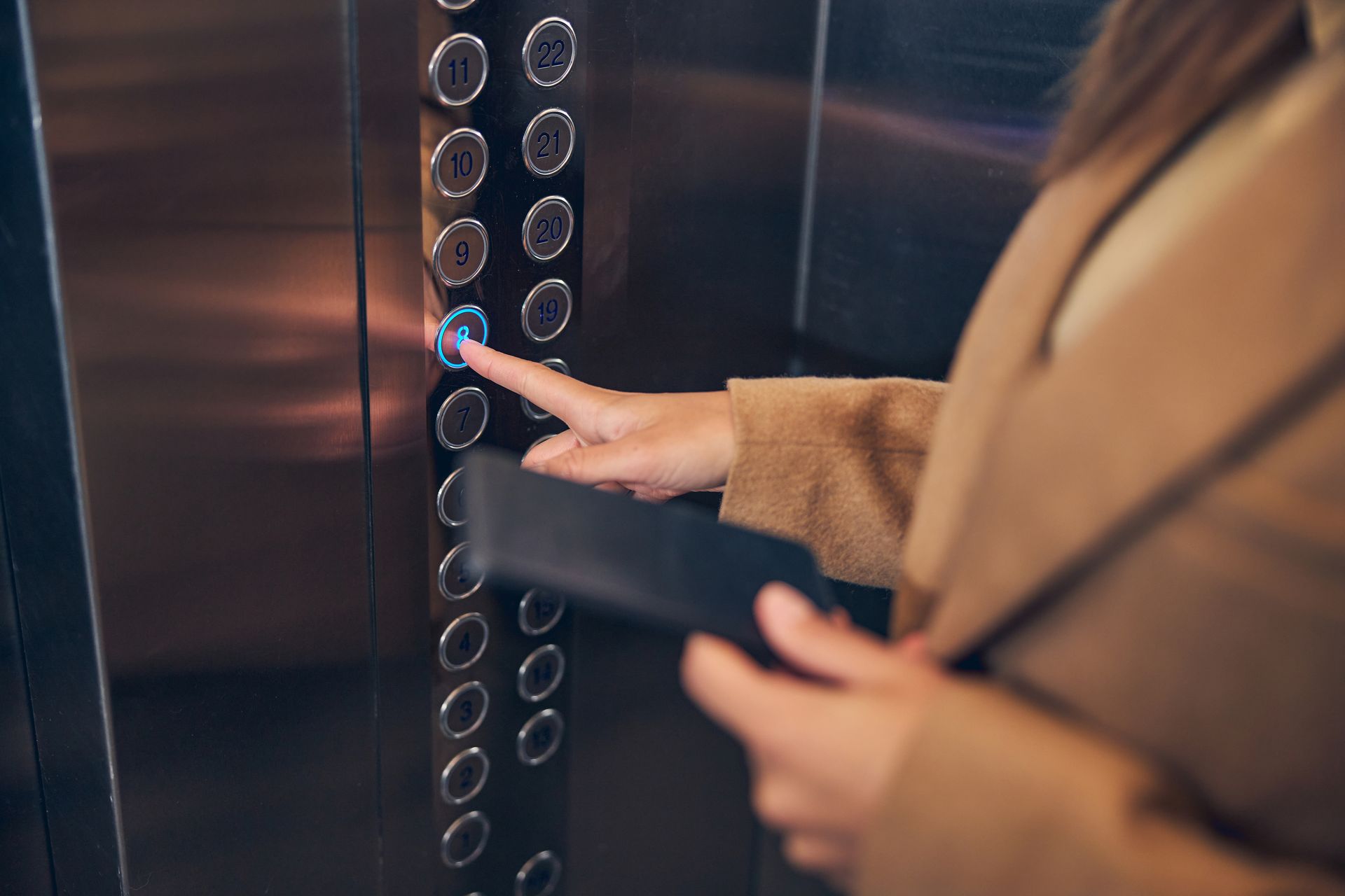 Doigt d'une salarié  sur le boutons 8 d'un ascenseur