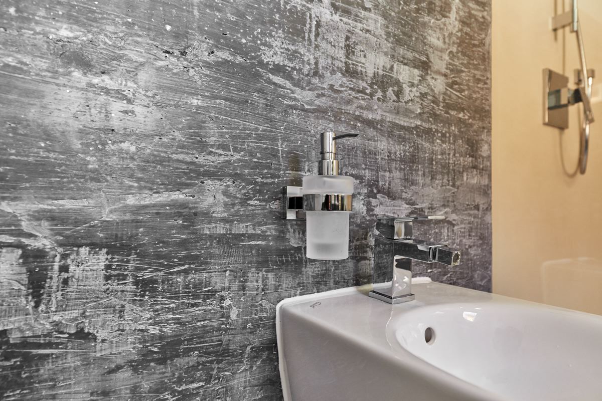 Helles Marmorbadezimmer mit Badewanne, Dusche, Waschtisch und Glastür in modernem Grau-Weiß-Design