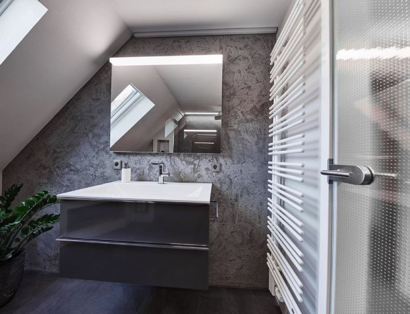 Modernes Badezimmer mit schwebendem Waschtisch, Wandspiegel, weißem Handtuchheizkörper und schrägem Dachfenster.