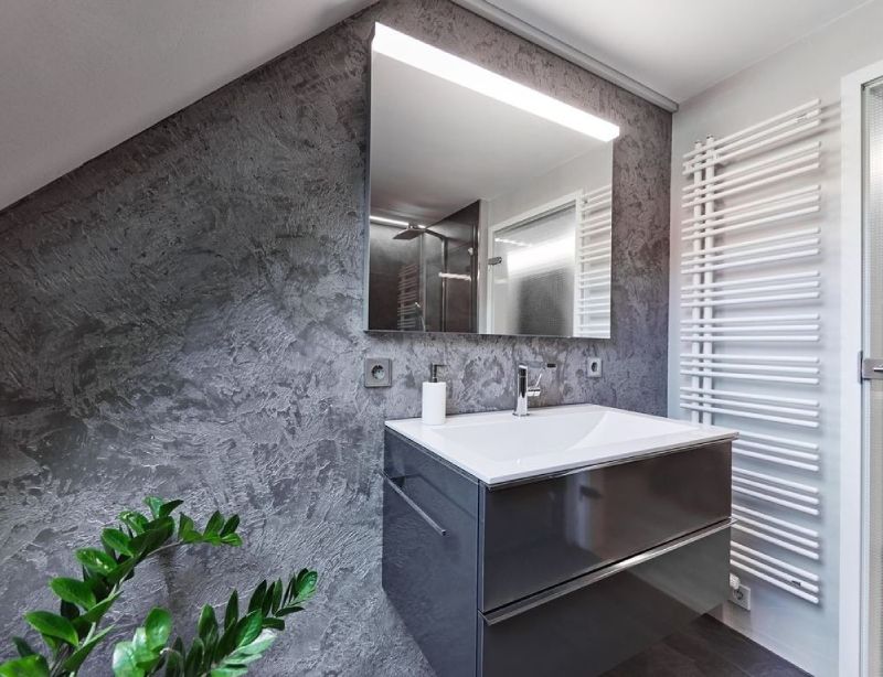 Modernes Badezimmer mit grauen, strukturierten Wänden, Waschtisch, Spiegel und weißem Handtuchwärmer