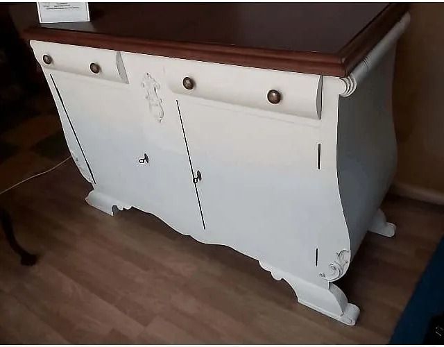 Un armario blanco con tapa de madera reposa sobre un suelo de madera.