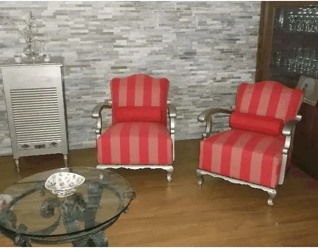 Una sala de estar con dos sillas de rayas rojas y una mesa de cristal.