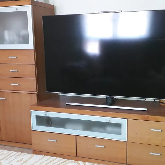 Un televisor de pantalla plana está sobre un centro de entretenimiento de madera.