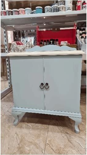 Un pequeño armario con dos puertas se encuentra sobre un suelo de baldosas en una tienda.