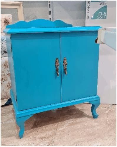 Un armario azul con tiradores dorados reposa sobre un suelo de baldosas.